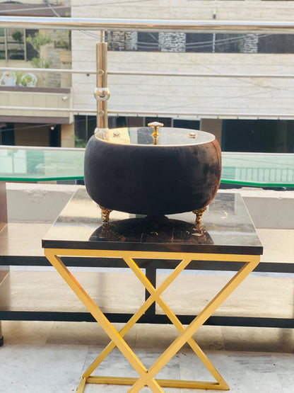 Decorative black and gold Turkish Hotpot on a marble table with a modern building in the background